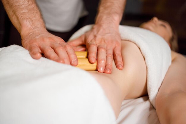 Woman in spa enjoying creole massage with bamboo sticks