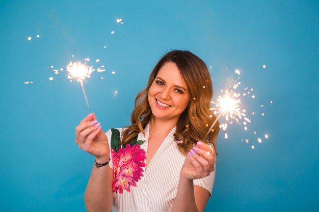 Woman Sparkler Celebration Happiness Firework Concept on blue background.