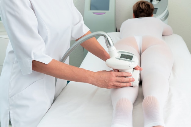 Woman in special white suit getting anti cellulite massage in a spa salon. LPG, and body contouring treatment in clinic.