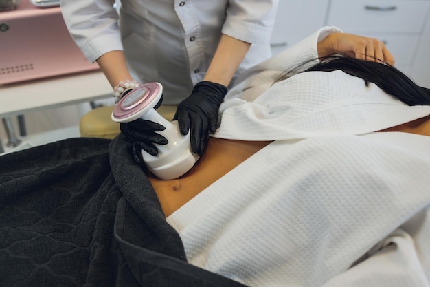 Woman in special white suit getting anti cellulite massage in a\
spa salon lpg and body contouring treatment in clinic