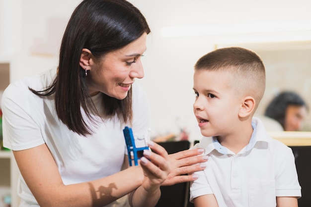 A woman speech therapist deals with the child and teaches him the correct pronunciation and competent speech.