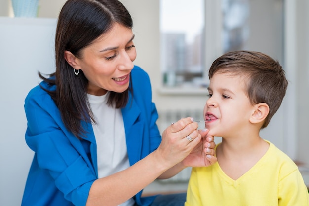 Woman speech therapist helps a boy correct the violation of his speech