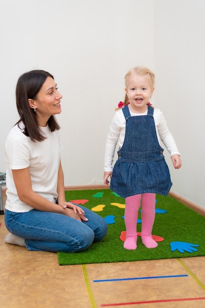 Woman speech therapist helps little girl to correct her speech in her office