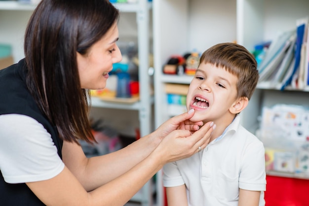 A woman speech therapist teaches a child to blow correctly on colored feathers