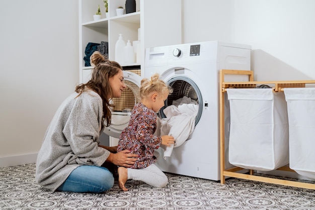 woman spends time with young child in laundry room bathroom performs household duties on maternity