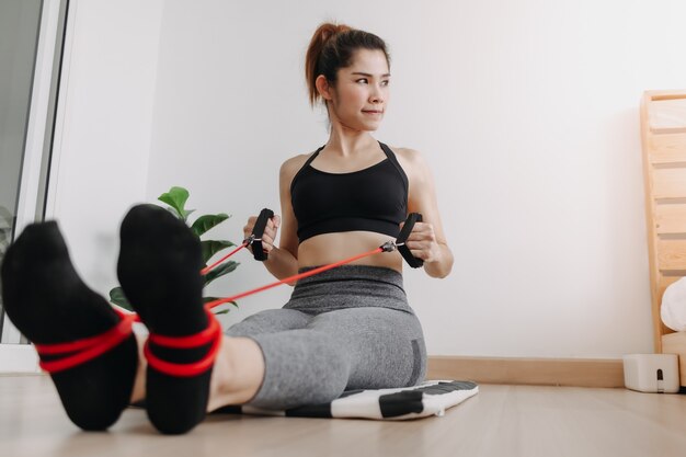 La donna nello sport indossa la fascia di resistenza seduta in fila prona nella sua stanza