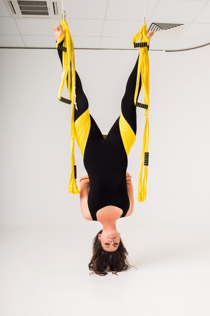 A woman in a sports jumpsuit does air yoga exercises