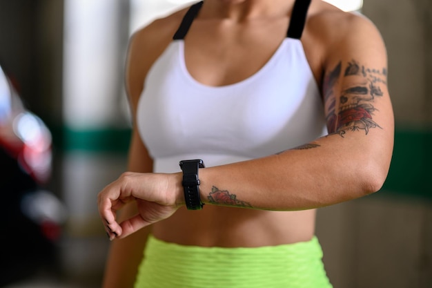 Woman in sportswear checks fitness and health tracking on her smartwatch after training