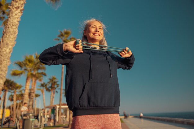 Foto donna in abiti sportivi che fanno le braccia che si allungano in piedi sulla riva del mare