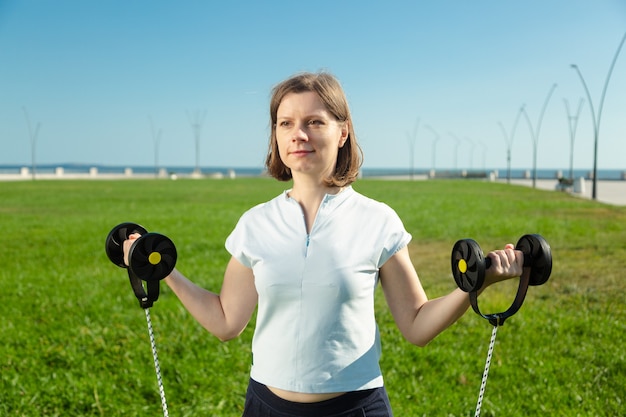 Woman in sportswear doing fitness exercises at green grass