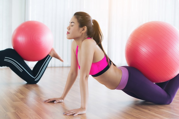 Woman in sportswear practice yoga workout stretching in indoors gym.