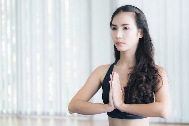 Woman in sportswear practice yoga workout stretching in indoors gym.