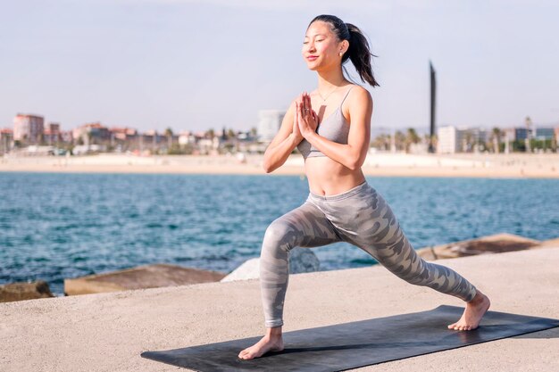 Woman in sportswear practicing yoga by the sea