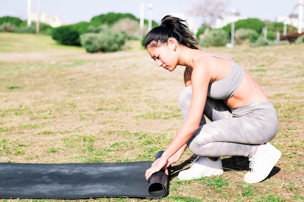 Женщина в спортивной одежде катается на коврике для сеанса йоги