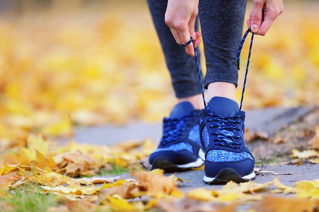 Woman in sportswear tying shoelaces on sneakers outdoor closeup