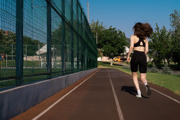 スポーツウェアを着た女性がスポーツスタジアムで運動をし外でジョギングをしているフィットな女性