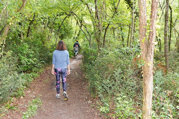 Woman sporty slim fit runner walking in forest outdoor trail in\
city park