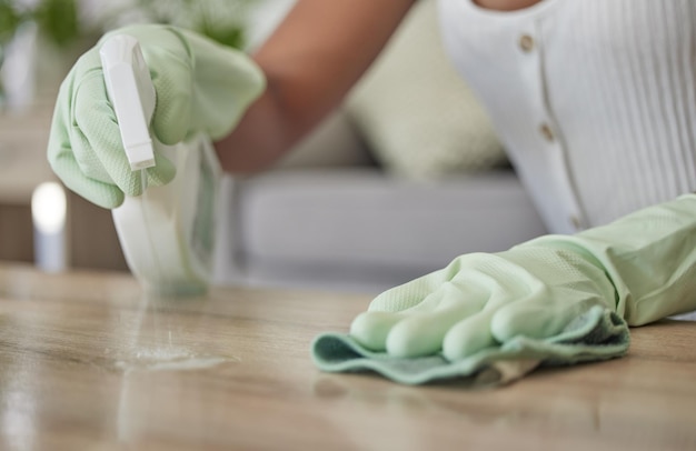 家庭でテーブルの表面を布や雑巾で拭くクリーナーでスプレーボトルと消毒剤を掃除する女性の手