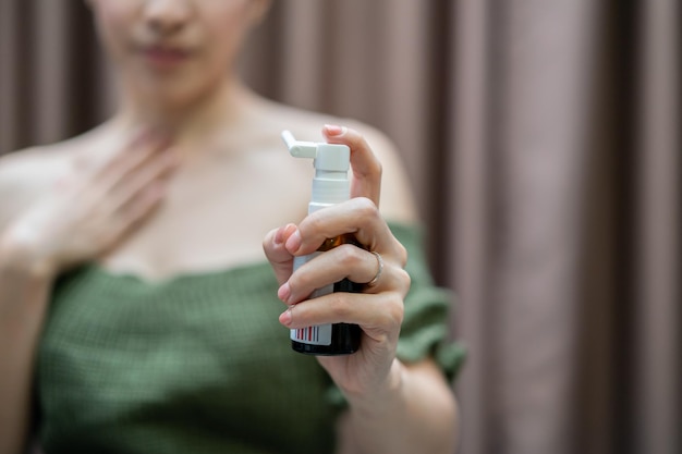 Photo woman spray for sore throat sprinkles it in her mouth