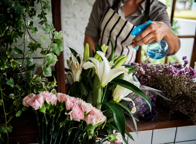 Женщина разбрызгивает цветы на освежающий напиток в магазине Flora