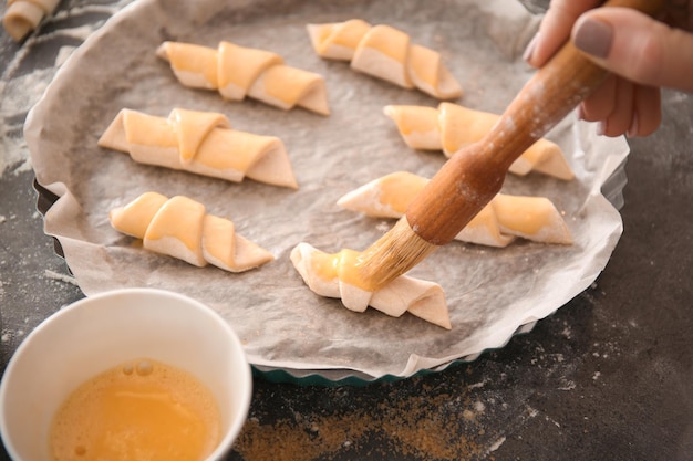 Woman spreading egg yolk on croissants closeup