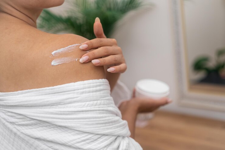 Woman spreading nourishing lotion on shoulder skin by fingers in bathroom lady body care treatment