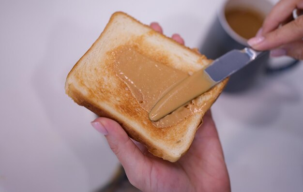 Photo woman spreading peanut butter on toast closeup