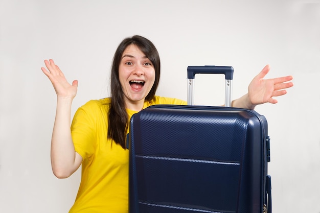 A woman spreads her arms to the sides in surprise near a suitcase