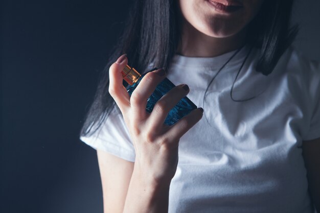 Woman sprinkles perfume on her neck