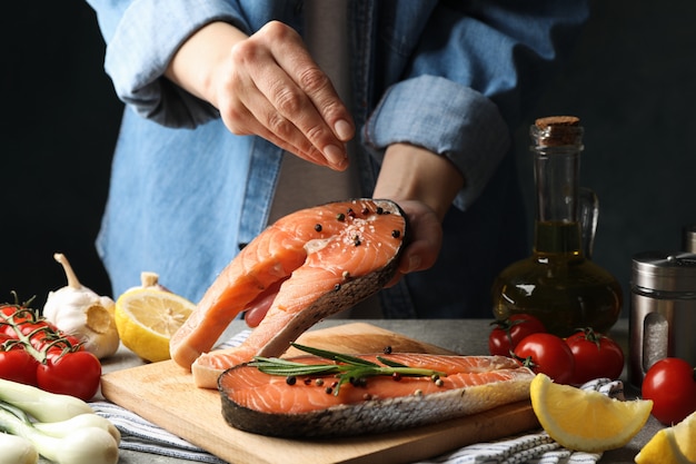 La donna spruzza il sale sulla carne di color salmone