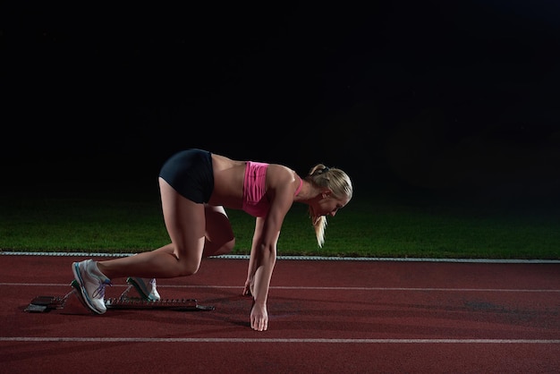 Velocista donna che lascia i blocchi di partenza sulla pista di atletica. vista laterale. inizio esplosivo