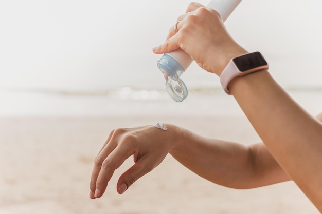 Photo woman squeezes sunscreen out of a tube on the sea beach uv protection
