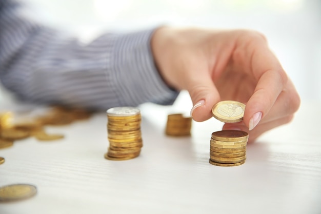 Woman stacking coins on table, closeup. Savings concept