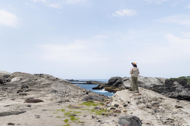 Woman stand on the rock and view the beach