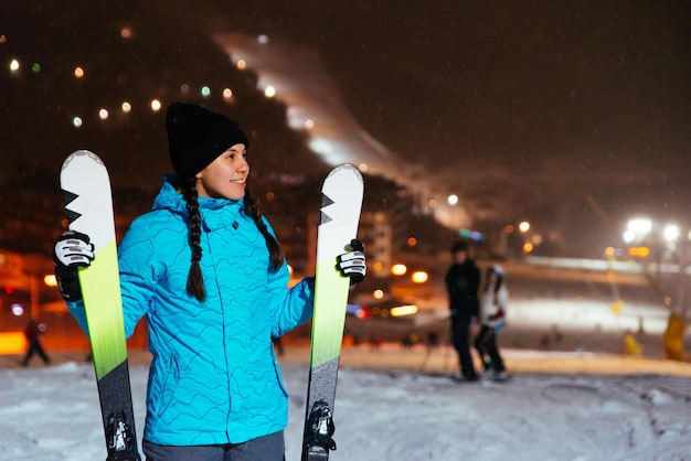 雪が降った丘の上にスキーを持って立っている女性