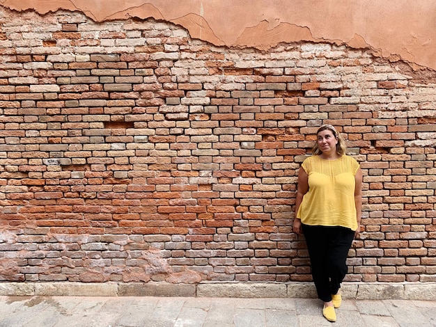 Woman standing against brick wall