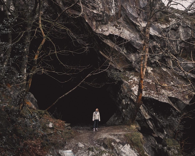 Женщина стоит у входа в пещеру.