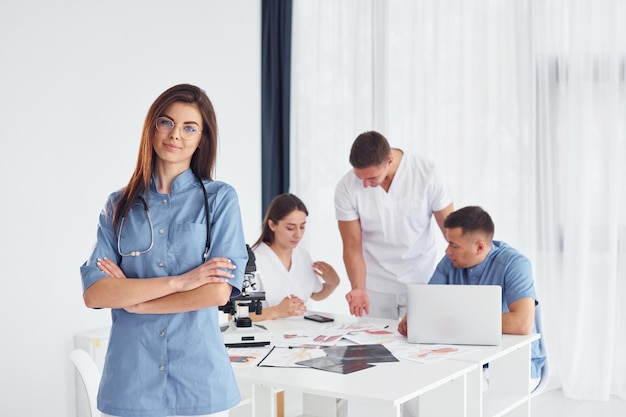 Woman standing against group of young doctors that is working together in the modern office