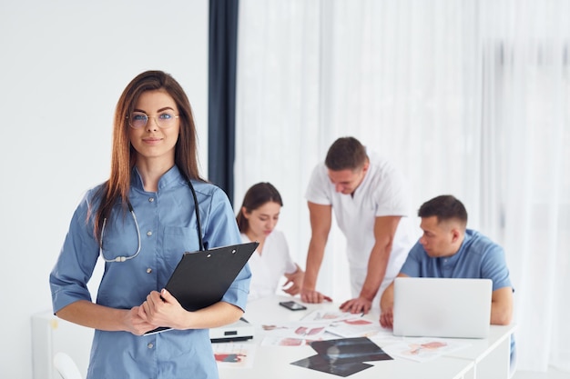 Woman standing against group of young doctors that is working together in the modern office