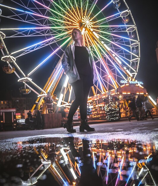 Photo woman standing against illuminated ferris wheel at night