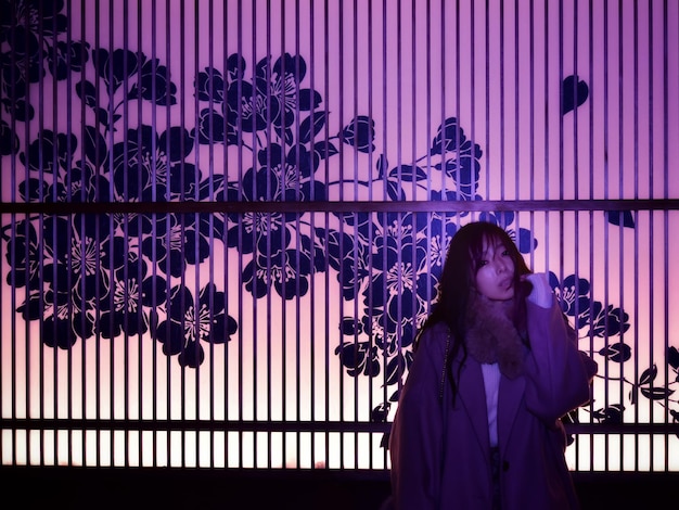 Woman standing against illuminated  wall