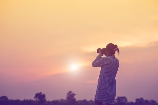 写真 オレンジ色の空に立っている女性