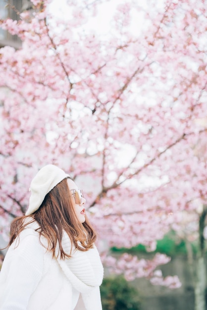 写真 ピンクのチェリーの花に立っている女性