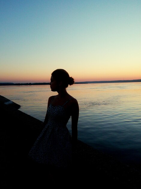 Foto donna in piedi contro il mare durante il tramonto