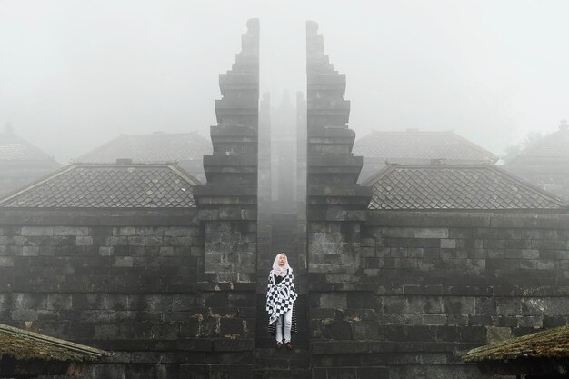 Фото Женщина, стоящая у храма во время туманной погоды