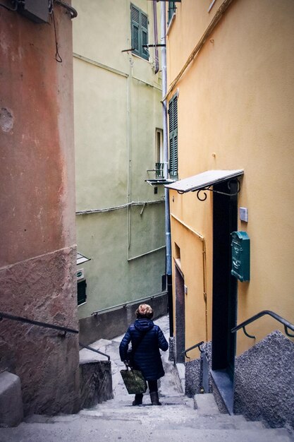 Foto donna in piedi in un vicolo tra gli edifici della città