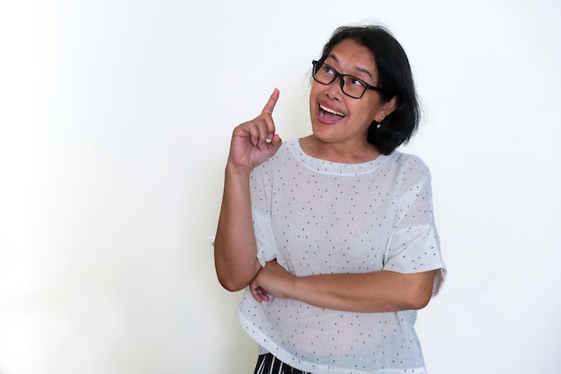 woman standing alone over white background with her finger pointing up expressing a new idea