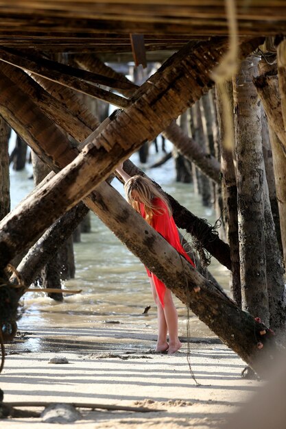 Woman standing amidst columns under pier at beach