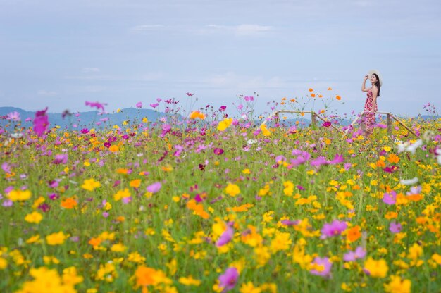 Woman standing amidst flowering plants on land against sky