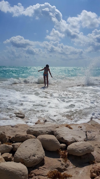 Woman standing amidst surf at seashore